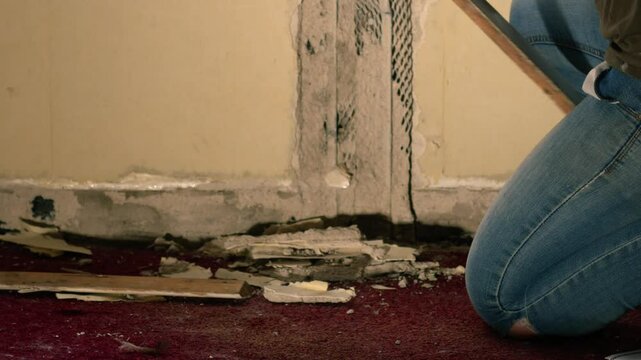 Removing old house baseboards with hammer and crow bar 