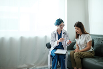 A woman is sitting on a couch while a doctor shows her a toothbrush