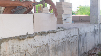 Workers use hammer to knock bricks into place. Masonry When building walls on building structures, stick with cement and be level.