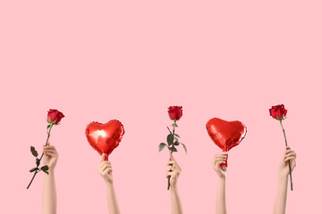 Female hands holding heart-shaped balloons and red roses on pink background. Valentine's Day celebration