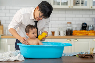 Asian baby taking a bath in a blue tub at home.