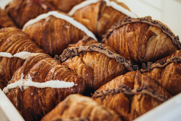 A box of freshly baked sweet croissants with fillings, close-up.