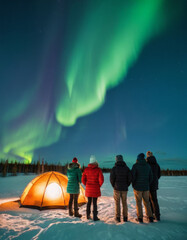 Group of travelers in warm clothes watching the Northern Lights in Arctic wilderness.