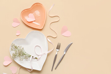 Table setting for Valentine's Day with heart-shaped plates, flowers, ribbon and paper hearts on...