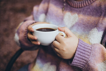 Woman drinking black filter coffee in cafe on terrace in autumn, close up.