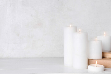 Burning candles and books on white wooden table