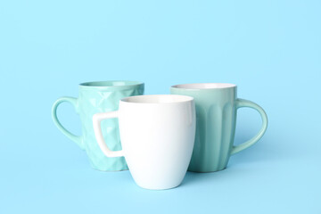 Different ceramic cups on blue background