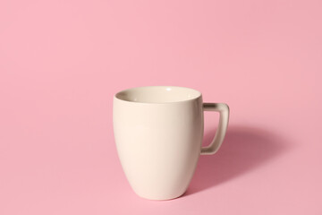 White ceramic cup on pink background