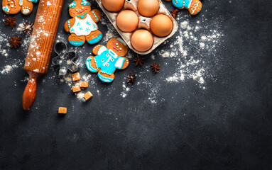 Top view of Christmas baking essentials with gingerbread cookies, rolling pin, eggs, and spices on...