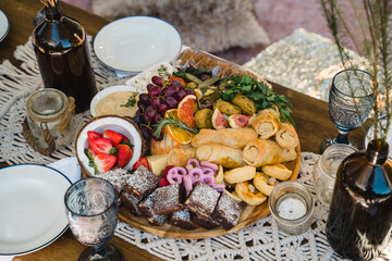 Outdoor party catering with finger food and fruits arranged on beautiful wooden outdoors furniture during summer
