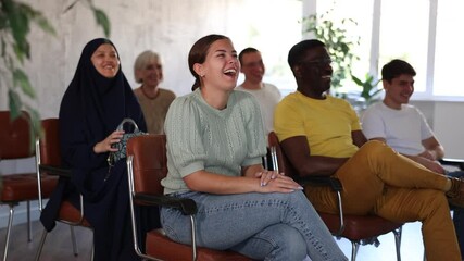 Young girl participating study session, sitting in auditorium with group of women and men on different ages and nationalities, listening to lecturer with interest