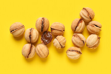 Many sweet walnut shaped cookies with boiled condensed milk on yellow background