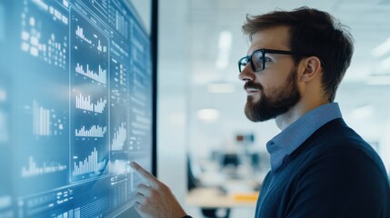 Fototapeta premium Focused Business Analyst Interacting with Modern Touchscreen Interface in a Bright Office Space Surrounded by Financial Charts and Data Visualizations