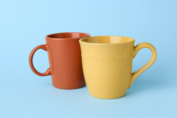 Brown and yellow empty ceramic mugs on blue background