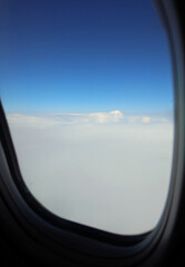 Naklejka premium white layer of clouds and blue sky seen through the window of a commercial airplane