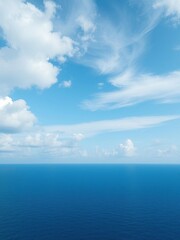 Fototapeta premium The cloudy blue sky gradually merges with the infinite blue line of the horizon above a tranquil ocean, sea, serene