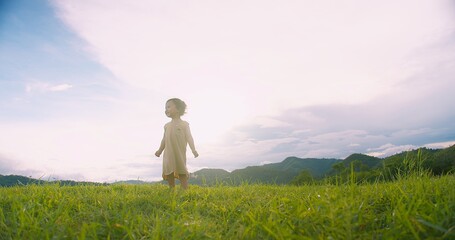 Fototapeta premium A young adorable child girl stands in a grassy field Sunlit Meadow gazing at the sky, Capturing a Sense of Wonder and Adventure in a Serene Natural
