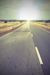 long and straight ran the asphalt road toward the sun with an antique effect ideal as a concept of travel and future