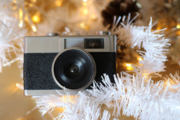 Old silver and black photo camera with Christmas decoration and lights