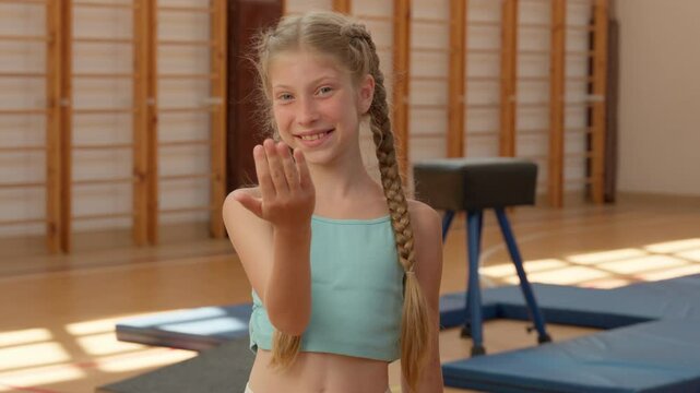 Happy schoolgirl little kid pupil smiling girl teen daughter child student school education sport class workout in gym invite join training female athlete gymnast young sportswoman alluring gesture