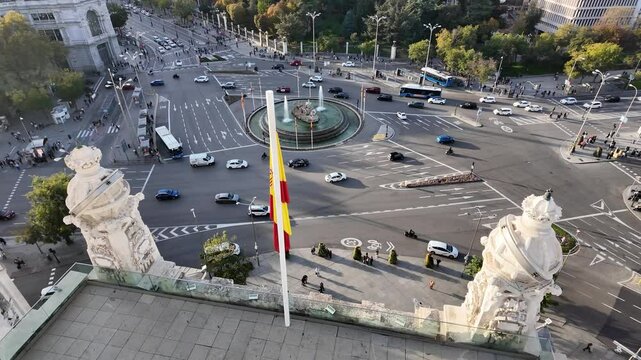 View of Palacio de Cibeles in Madrid on a sunny day, featuring historic architecture, traffic, and a vibrant urban setting.
