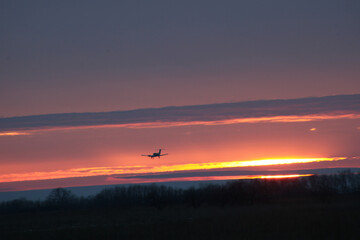 The plane lands at sunset. The photo shows the plane, clouds and a beautiful sunset