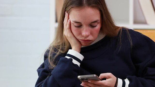 young woman or girl bored looking at her mobile phone