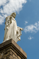 Obraz premium une statue blanche de la sainte vierge Marie vue en extérieur en contre plongée avec un ciel bleu nuageux 
