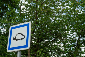 panneau bleu de signalisation d'un emplacement de parking avec une borne de recharge pour les...