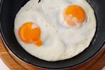 Fried eggs in a frying pan, close-up macro, isolated on white