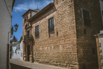 Historic stone building in a narrow street of Ronda, Spain, under a clear blue sky