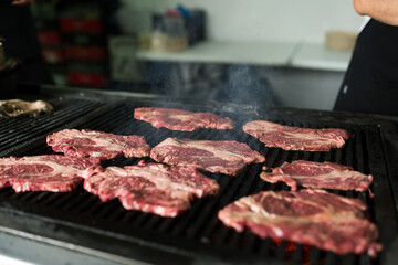 Beef steaks sizzling on a hot grill in a commercial kitchen, capturing the delicious aroma as they cook