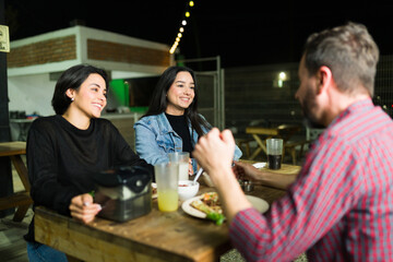 Group of friends having a lively chat over tacos and drinks at an outdoor mexican taqueria
