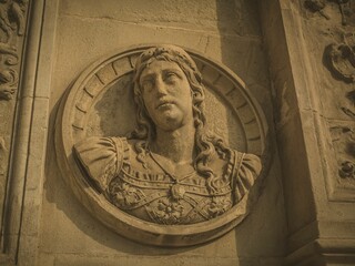 Ancient stone relief sculpture of a Roman figure on a textured wall in Andalusia, Spain