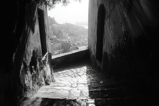 A sunlit alleyway reveals a distant coastal town - Powered by Adobe