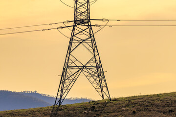 Photograph of the bottom section of an electricity Transmission Tower against an orange sunset sky in regional Australia.