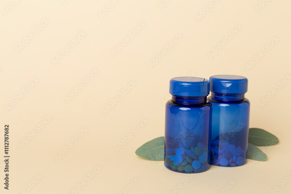 Sticker Bottles with pills and green leaves on color background