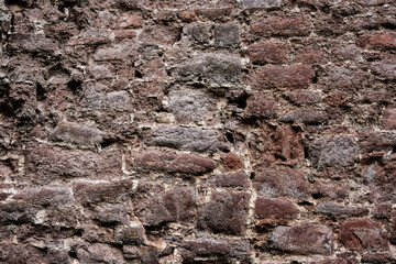 A wall made of stone with a rough texture. The wall is brown and white