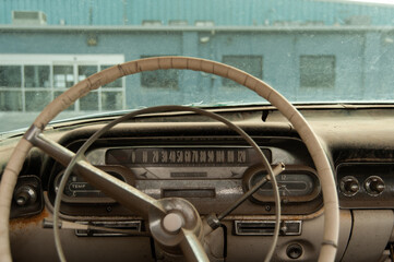 Vintage car dashboard with worn steering wheel and dusty interior