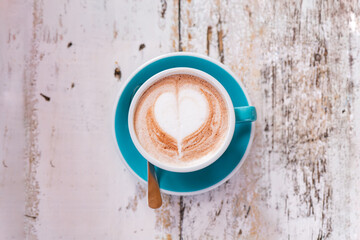 Cappuccino with heart latte art on rustic white wooden table
