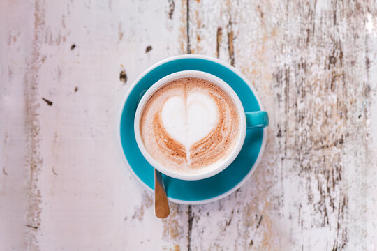 Cappuccino with heart latte art on rustic white wooden table