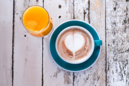 Cozy latte art and fresh orange juice on rustic table setting