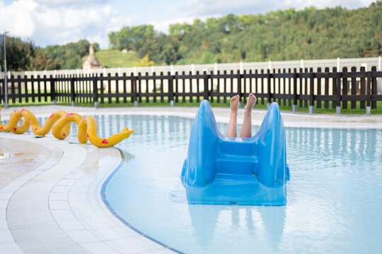Child Playing on Blue Slide by Outdoor Pool with Float