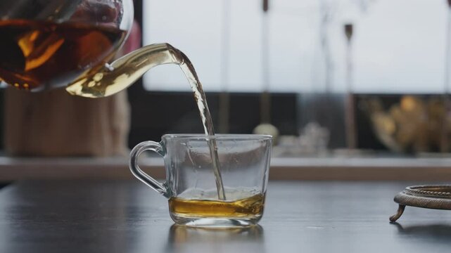Close-up of a man pouring hot tea into a cup