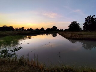 A serene river view with the sun rising or setting over calm waters and vibrant skies