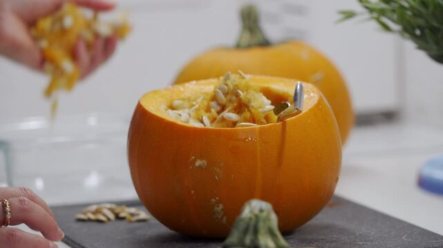 Woman preparing stuffed red kuri squash in the kitchen. Stuffed orange colored winter squash for baking in the oven.