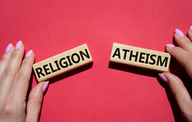 Religion or Atheism symbol. Concept word Religion or Atheism on wooden blocks. Businessman hand. Beautiful red background. Business and Religion or Atheism concept. Copy space