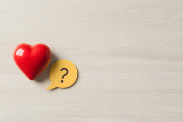 Obraz premium A Red Heart-Shaped Object and a Yellow Question Mark, Symbolising Curiosity and Love in a Creative and Bold Design