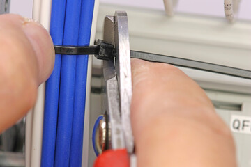 Cutting plastic ties on insulated wires with a tool.