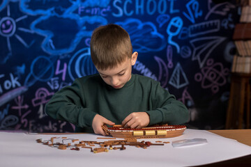 Boy working on a ship model project with a creative classroom backdrop. A perfect image for education, creativity, and school-related content.